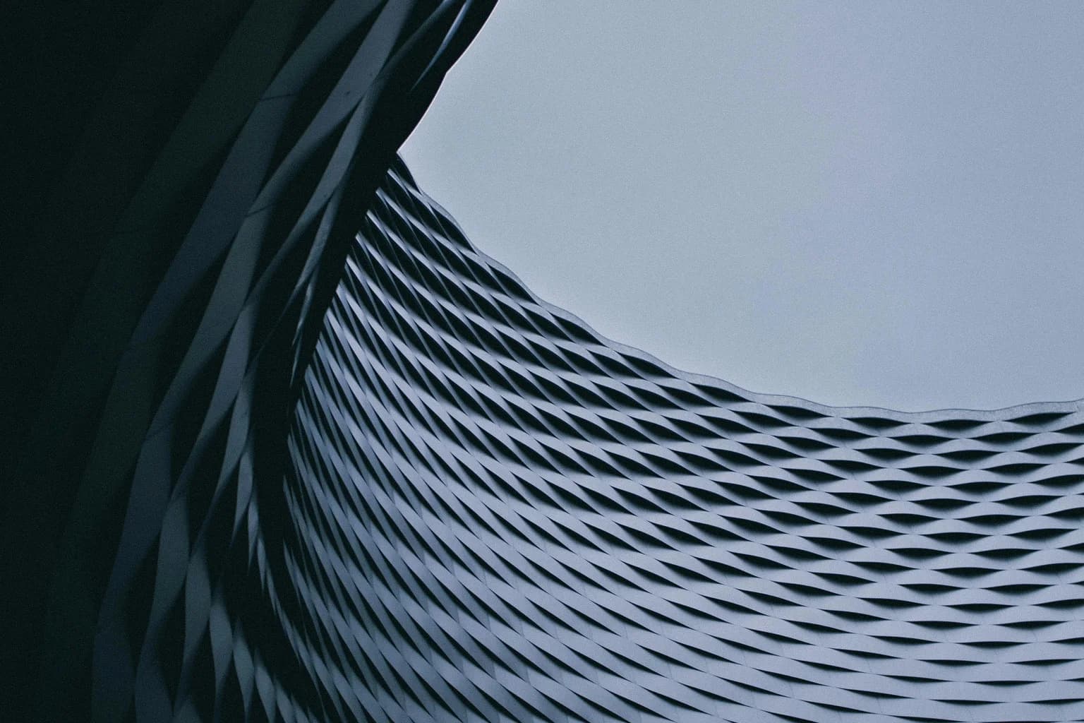 Curved architectural forms meet beneath an open section of sky.