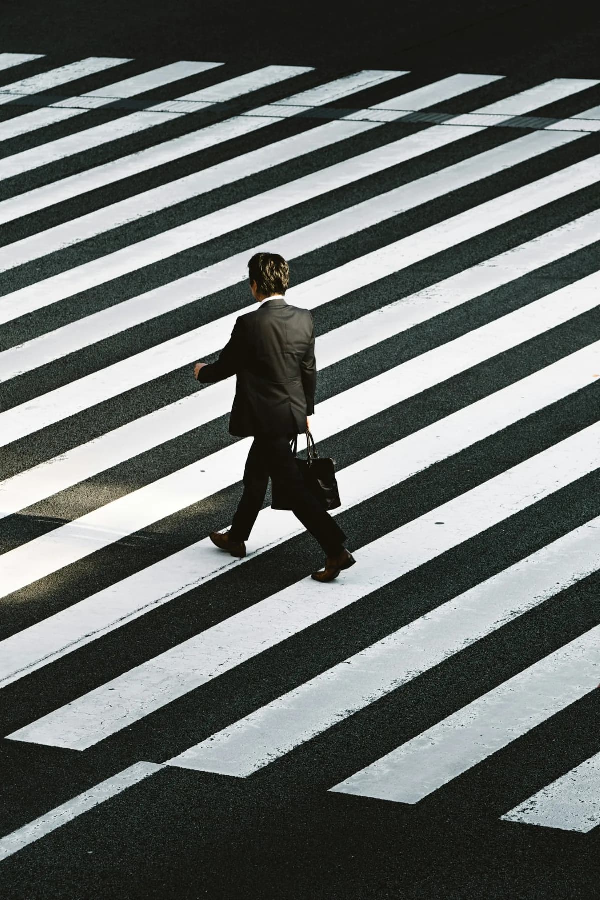 A business professional crossing a wide striped road.