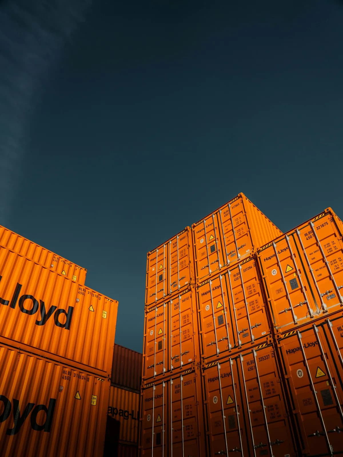 Stacks of orange shipping containers beneath a dark sky.
